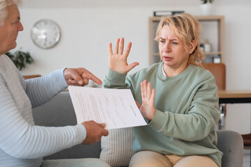 Mature woman refusing to sign divorce decree from her husband at lawyer's office