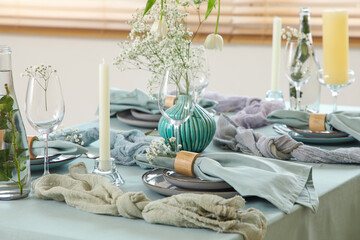 Elegant table setting with beautiful flowers, candles and folded napkins in restaurant