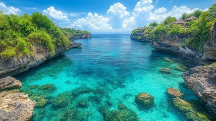 beautiful beach in Bali, with a blue sea and sky, had an overlooking view of green trees on both sides of the cliff and rocks below, with clear water © Frame Stocks
