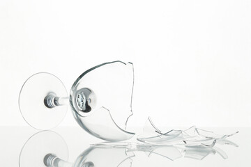 Pieces of broken wine glass on table against white background, closeup