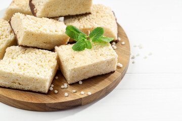 Delicious puffed rice bars and mint on white wooden table, closeup
