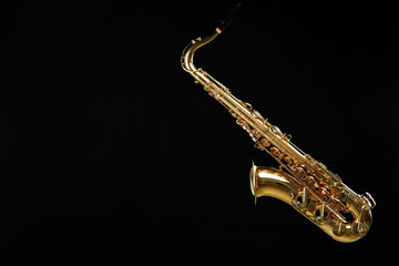 Obraz premium Jazz. One beautiful saxophone hanging from strap on black background, space for text