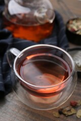 Delicious herbal tea and dry leaves on wooden table, closeup
