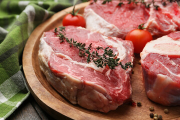 Pieces of raw beef, tomatoes and spices on wooden table, closeup