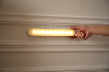 Woman turning on LED lamp at home, closeup