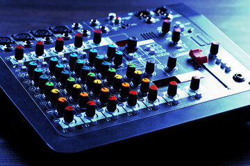 Professional DJ mixer on table in blue light, closeup