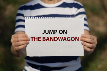 Jump on the bandwagon text on notebook paper holding by a woman