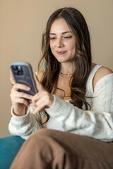 Young beautiful woman sitting at home using her phone