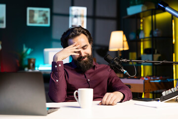 Influencer in home studio doing live broadcast for online streaming platforms, talking with fans, sharing embarrassing story. Blushing media star feeling flustered while telling viewers about himself