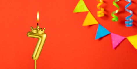 Number 7 birthday candle on an orange background with pennants