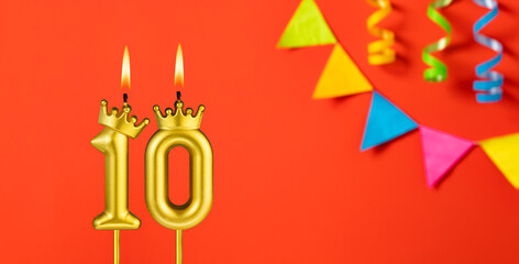 Number 10 birthday candle on an orange background with pennants
