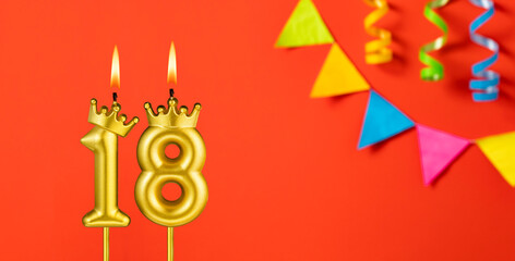 Number 18 birthday candle on an orange background with pennants
