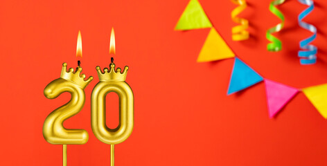 Number 20 birthday candle on an orange background with pennants