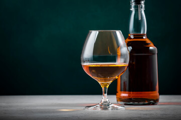 French cognac V.S.O.P. in snifter glass with bottle on dark green background