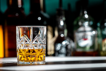 American tennessee whiskey in glass and bottles of strong drinks on dark green background, hard...