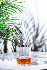 Japanese blended whiskey in glass. White  background with tropical leaves, hard light
