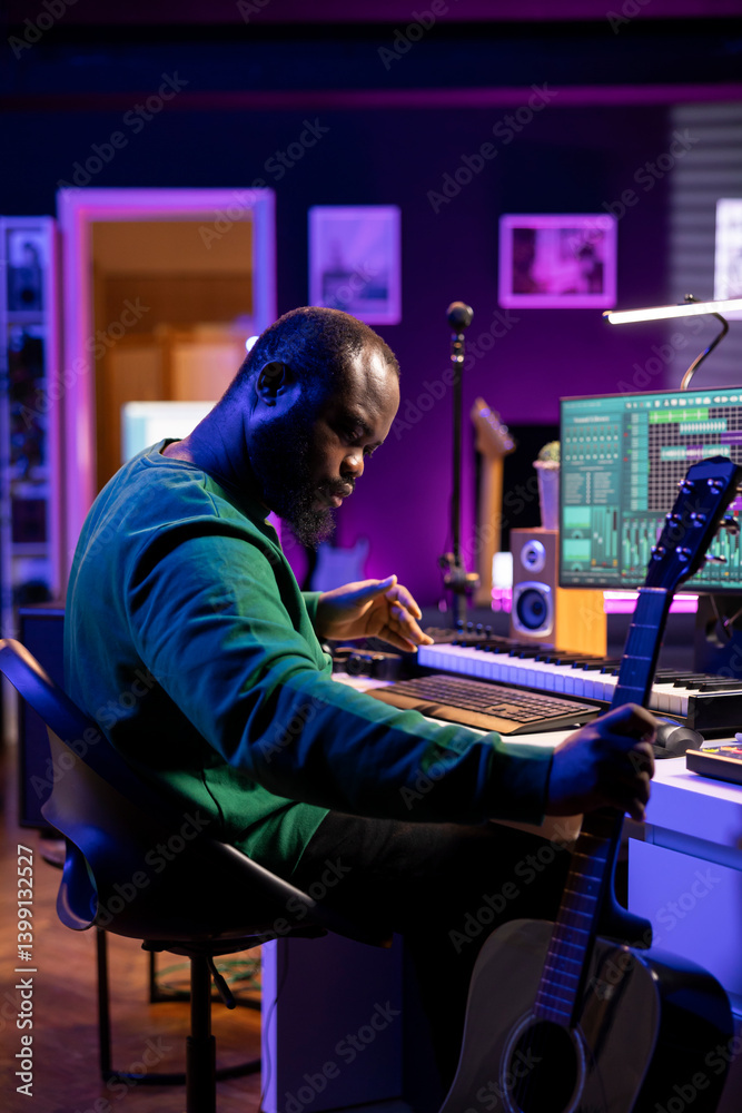 Poster musical composer recording his acoustic guitar notes in home studio, creating an amazing track by si