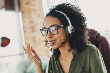 Professional young businesswoman with headset smiling while working in an open and modern office...