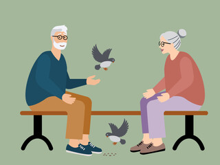 Senior man and woman feeding birds in the park  