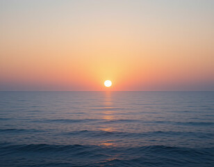 Obraz premium A serene and peaceful view of the ocean at sunset, with the sun gently setting on the horizon, casting soft, warm hues of orange and pink across the calm water.