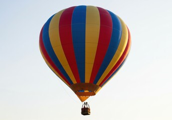 Fototapeta premium A colorful hot air balloon with red yellow and blue stripes against a bright white sky background