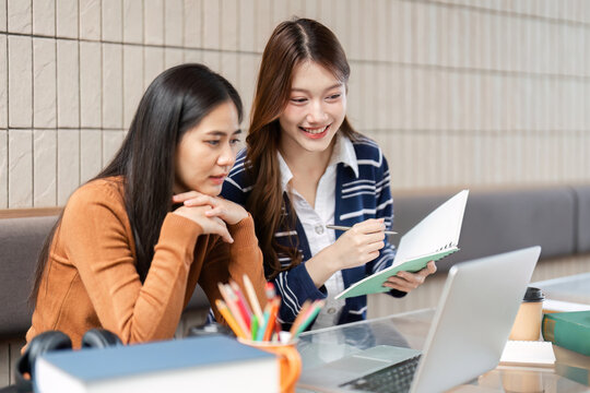 Academic Engagement and Support. Two young women discussing study materials while reviewing notes on a laptop.