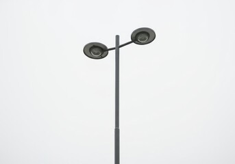 A minimalist view of a two headed street lamp against a white sky in a simple composition style