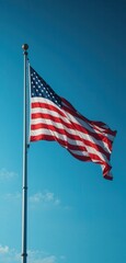 A vibrant flag flutters gracefully in the breeze against a clear blue sky, its colors vivid and bold, symbolizing unity and pride as it dances in the sunlight.