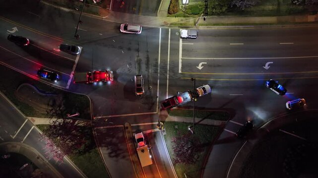 Emergency night scene on motorway at night. Car crash with police, fire trucks and ambulance with flashing.Aerial top down shot. Injured people in vehicles on junction. Suburb of Virginia, USA.