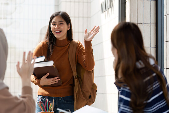 Student Arrival and Greeting. A student enters a cafe, greeting friends with enthusiasm and books in hand.