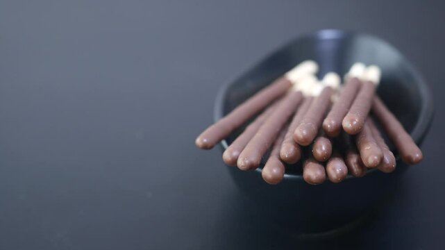 Chocolate coated snacks in a bowl on a dark table