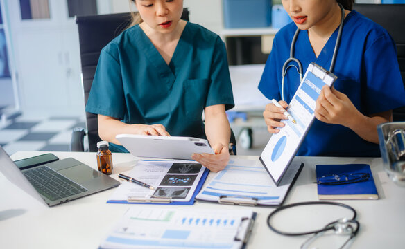 Two doctors and a female nurse meet at a table in the hospital, collaborating on medical tasks using laptops and computers