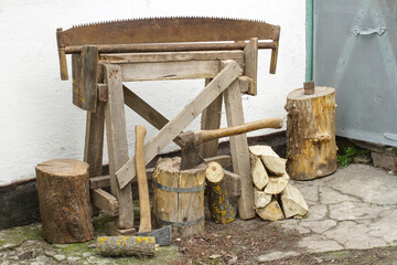 Equipment for manual chopping of firewood. Firewood, axes and a saw. Old firewood supplies.