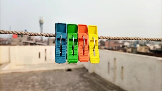 Multicolor plastic clothes pins or clothes pegs for house hanging on rope on roof top, laundry clips set, front view