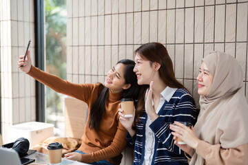 Memories and Moments. Friends capture a fun selfie during their studying session in a trendy cafe.