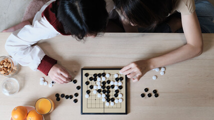 Close-up and top-view shots of GO, oriental checkers board game on wooden table are played by two...