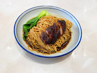chinese cook hong kong dry wanton roasted bbq char siew meat yellow egg noodle mee in dark soy sauce in plate on white marble table asian restaurant halal food cafe menu