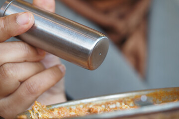 Close-Up of a Hand Holding a Stainless Steel Spice Shaker