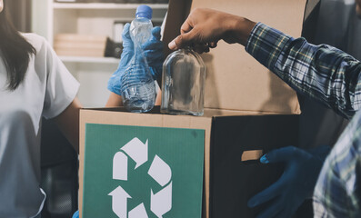 Close-up of female hands from a family collecting plastic waste and bottles from the ground. They...