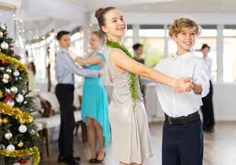 Couples dancing - teenagers in festive clothes dance the Viennese waltz near the Christmas tree