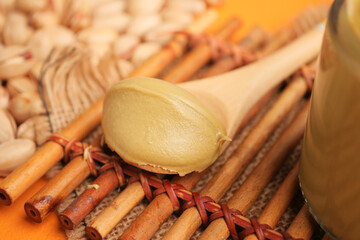 Pistachio butter spread on a wooden spoon with nuts background