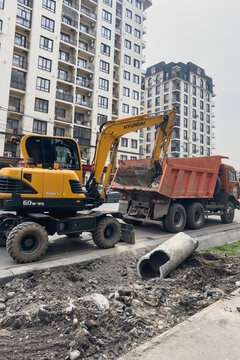Bishkek, Kyrgyzstan - April 9, 2025: An excavator loads soil into a dump truck during road repairs.