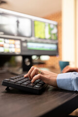 Closeup of a person using computer keyboard at office desk during their video editing session. Selective focus on female hands seated at workstation, typing and improving film montage visual quality.