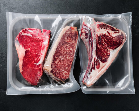 Products made of meat in plastic packaging, vacuum-dried aged steak against a dark stone background