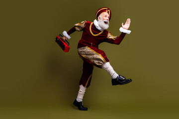 Mature man in royal medieval costume dancing with boombox against khaki background