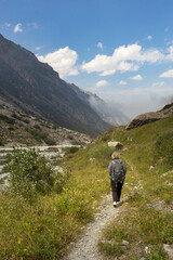 Solo female traveler trekking through the scenic mountainous landscape of Ala Archa National park...