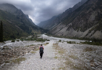 Solo female traveler trekking through the scenic mountainous landscape of Ala Archa National park...