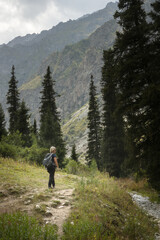 Obraz premium Solo female traveler trekking through the scenic mountainous landscape of Ala Archa National park in Kyrgyzstan