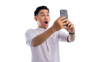 Surprised Asian Muslim man looking at mobile phone screen reacting to online news isolated on transparent background