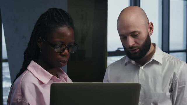 Medium shot of young diverse employees in formalwear using laptop at office workspace